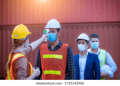 The Worker Used A Medical Digital  Temperature Thermometer To Check Staff Body Temperature Before Start Work In Factory ,they Wearing Face Mask The Concept Of A Corona Virus [Covid-19] Screening.