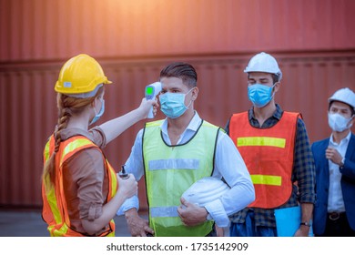 The Worker Used A Medical Digital  Temperature Thermometer To Check Staff Body Temperature Before Start Work In Factory ,they Wearing Face Mask The Concept Of A Corona Virus [Covid-19] Screening.