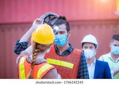 The worker used a medical Digital  temperature Thermometer to check staff body temperature before start work in factory ,they wearing face mask the concept of a corona virus [Covid-19] screening. - Powered by Shutterstock