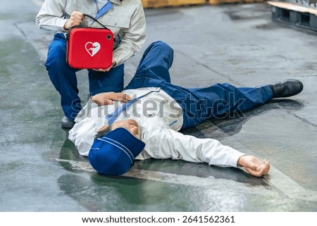 A worker uses an AED to help a man who collapsed at a factory