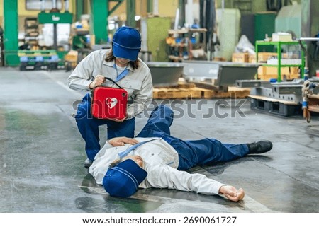 A worker uses an AED to help a man who collapsed at a factory