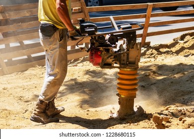 Worker Uses Compactor To Firm Soil At Worksite