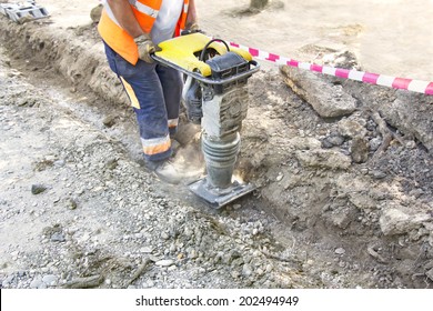 Worker Uses Compactor To Firm Soil At Worksite