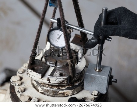 ​A worker uses a dial indicator and a specialized jig to precisely measure a backlash output flange differential.
