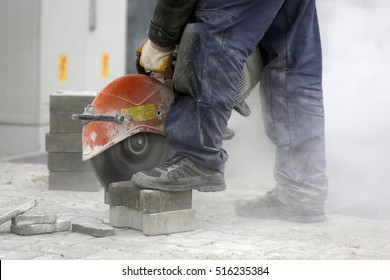 Worker uses a stone cutter to cut the brick pavers. Cutting concrete paving stabs using a cut-off saw. Paving stone saws working with power tools. 
