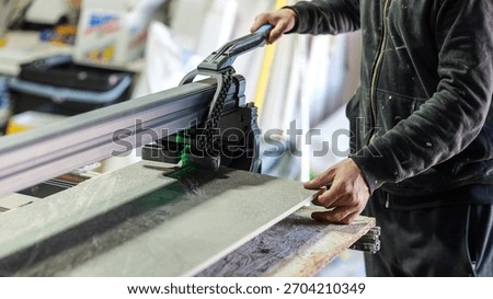 A worker uses a tile cutter to precisely cut a tile for a home renovation project
