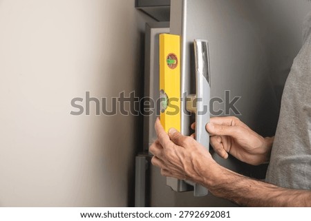 Worker using bubble level on fridge at home.