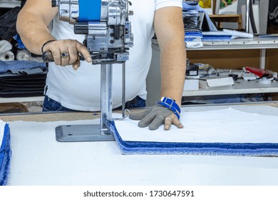 Worker using a cutter - a large machine for cutting fabrics -  in a textile factory, he wears a chain glove.
