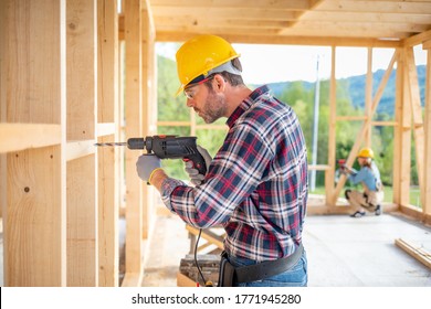 Worker Using Drill Working On Construction Of Wood Frame House