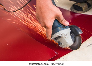 Worker using a grinding machine to cut a metal plate