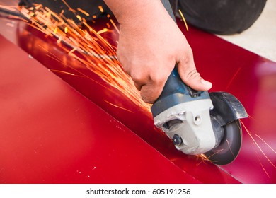 Worker using a grinding machine to cut a metal plate