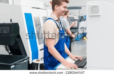 Worker using keyboard to enter data into a machine on factory floor