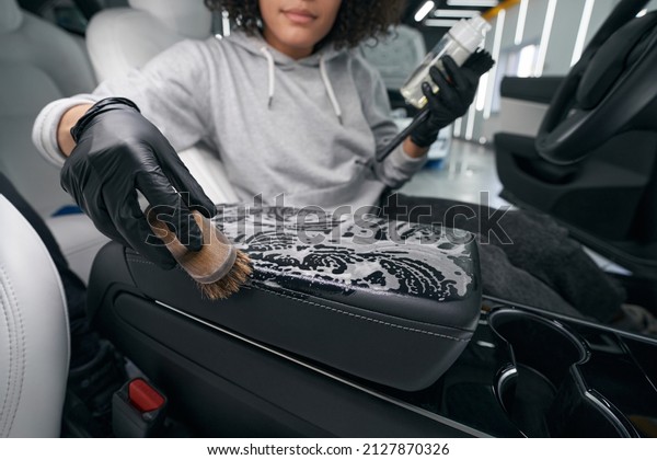 Worker using leather cleaner and brush for\
cleaning car upholstery
