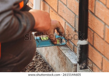 Worker using level tool to check accurate brick alignment