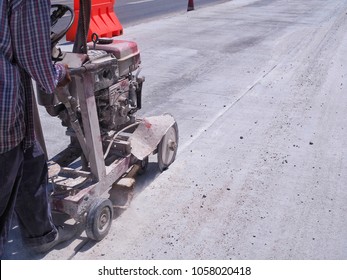 Worker is using the old cutter machine make a road to the groove for put the liquid asphalt in the concrete street construction area