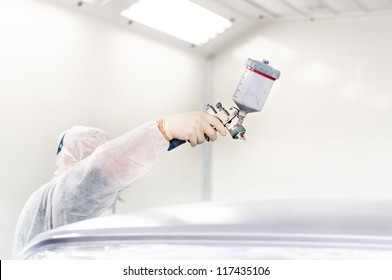 Worker Using A Paint Spray Gun For Painting A Car In A Special Booth