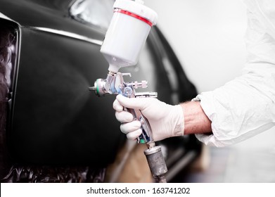 Worker Using A Paint Spray Gun For Painting A Car