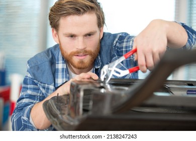 Worker Using Pliers To Repair A Car Door