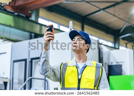 A worker using a portable measuring device in a factory