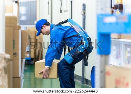 A worker using a power assist suit in a warehouse.