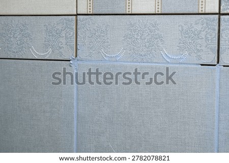 Worker using a rubber grout float to smooth grout between tiles. Carefully applying sealant to tiles joints. Workman hands smoothing caulk, using small tool to remove excess and create clean seam.
