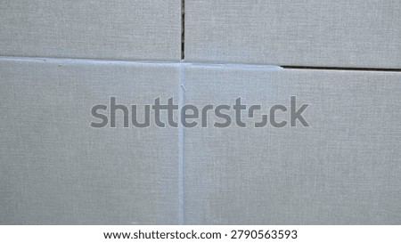 Worker using a rubber grout float to smooth grout between tiles. Carefully applying sealant to tiles joints. Workman hands smoothing caulk, using small tool to remove excess and create clean seam.