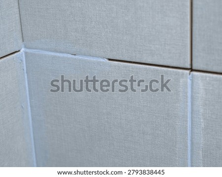Worker using a rubber grout float to smooth grout between tiles. Carefully applying sealant to tiles joints. Workman hands smoothing caulk, using small tool to remove excess and create clean seam.