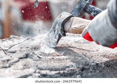 Worker using a sledgehammer to cut a stone with cement. Construction site worker
