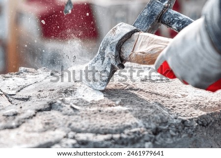 Worker using a sledgehammer to cut a stone with cement. Construction site worker