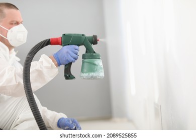 Worker Using Spray Gun For Coloring Wall In White. Effective And Fast Way To Paint Wall