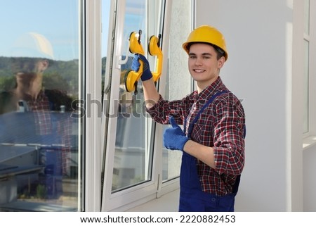 Worker using suction lifters during plastic window installation indoors