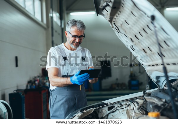 worker using\
tablet for car diagnostic\
service