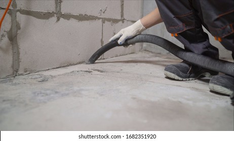 Ein Arbeiter, der einen Staubsauger verwendet, entfernt Bauschutt. Ein Arbeiter reinigt Industrieräume. Wohnung nach Reparatur mit Polysos.