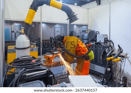 Worker using welding equipment in a workshop with sparks flying, wearing protective gear and fume extraction system. – Metalworking, Industrial Manufacturing