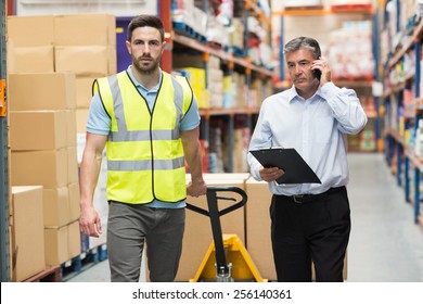 Worker walking with his manager over the phone in warehouse - Powered by Shutterstock