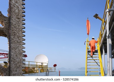 Worker Walking Up Stairs To Oil Rig's Helipad To Check Over Before Moving Rig To Other Location With Mountain