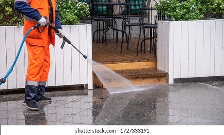 Worker washes the sidewalk in front of a street cafe - surface sanitation - Powered by Shutterstock