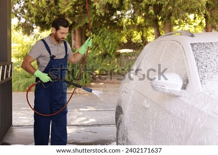 Worker washing auto with high pressure water jet at outdoor car wash [[stock_photo]] © 