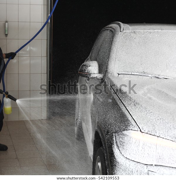 The worker washing of the car under a high\
pressure. Car service.