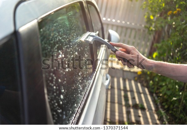 worker washing the\
car window with a\
scraper