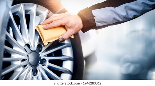 Worker Washing Car's Alloy Or Alluminium Wheels On A Car Wash. Rims Detailing Using Cleaning Yellow Cloth.