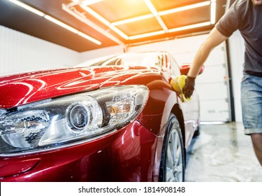 Worker washing red car with sponge on a car wash - Shutterstock ID 1814908148