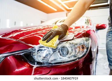 Worker washing red car with sponge on a car wash - Shutterstock ID 1840407919