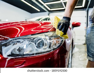 Worker washing red car with sponge on a car wash - Shutterstock ID 1859192500