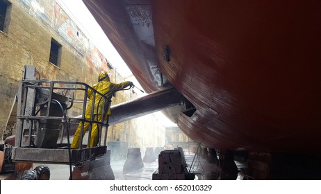 worker washing ship hull at drydock