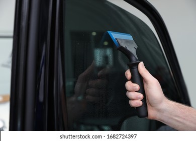 Worker Washing Tinted Car Window In Workshop, Closeup