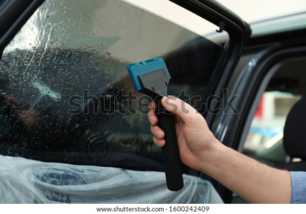Worker\
washing tinted car window in workshop,\
closeup