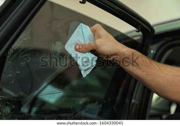 Worker
washing tinted car window in workshop,
closeup