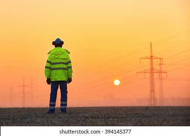 Worker Is Watching Electricity Pylons And Substation At The Sunrise