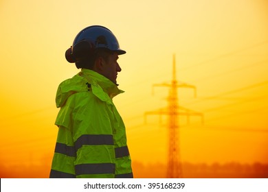 Worker Is Watching Electricity Pylons And Substation At The Sunset